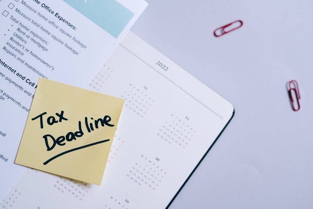 A sticky note reading 'Tax Deadline' on a desk calendar