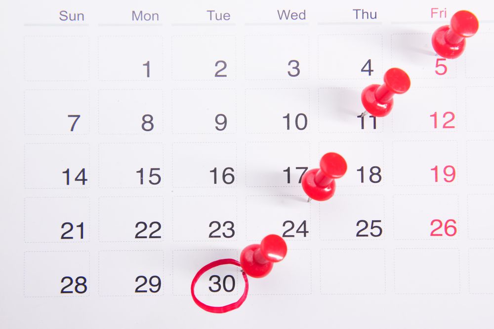 A calendar with a date circled in red and marked with push pins